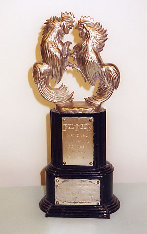 Two gold roosters on a trophy