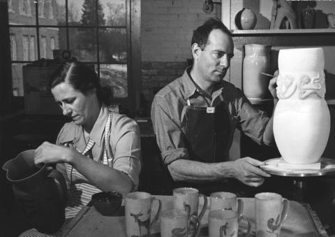black and white photo of woman and man making pottery in a studio